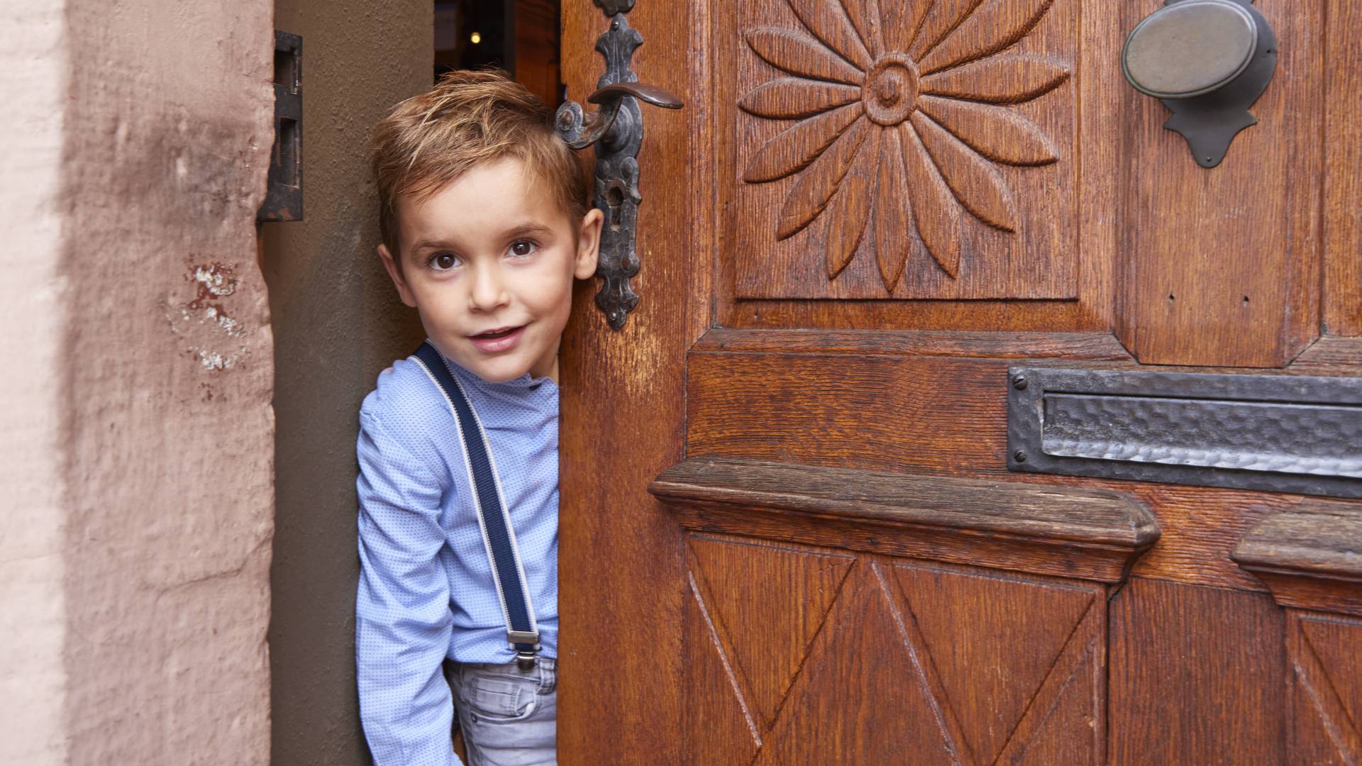 Kleiner Junge schaut durch Holztür