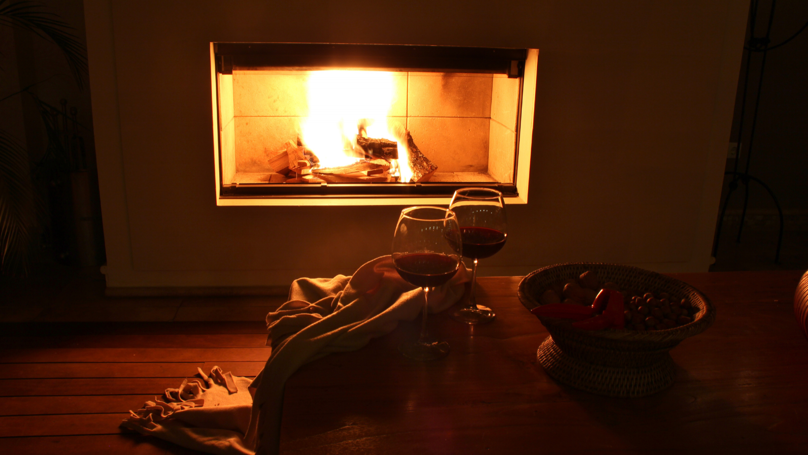 Tisch mit Rotwein und Nüssen vor dem Kamin