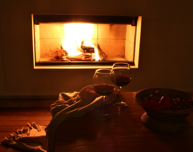 Tisch mit Rotwein und Nüssen vor dem Kamin